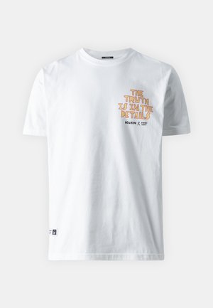 T-shirt bianca a maniche corte con testo arancione "La verità sta nei dettagli" e testo nero più piccolo sotto nella zona sinistra del petto.