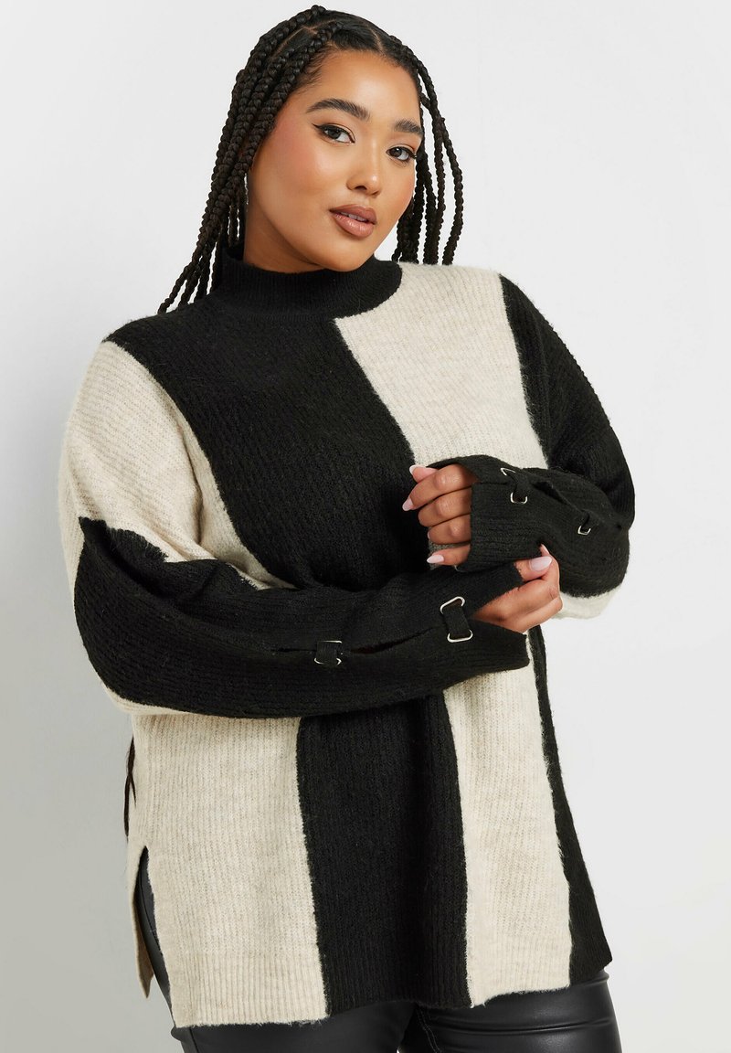 Czarny i kremowy sweter w pionowe paski, o prążkowanej fakturze, z wysokim dekoltem, z rękawami z wycięciami z metalowymi akcentami i bocznymi rozcięciami.
