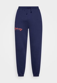 Mörkblå bomullssweatpants med elastiska manchetter, dragsko i midjan och röd broderad text som står "Grimey Mud City" på framsidan.