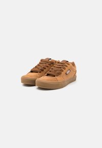 Brązowe zamszowe trampki w niskim fasonie, z okrągłymi sznurówkami, wyściełanym językiem i gumową podeszwą. Logo na boku.