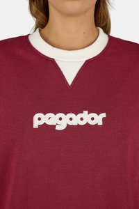 Bordó kapucnis pulóver fehér bordás gallérral és V-nyakkivágással, fehér hímzett "pegador" logóval.
