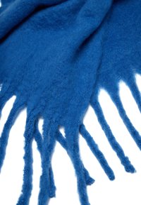 Sciarpa di lana blu con una texture morbida, caratterizzata da frange appuntite lungo i bordi, che mostra una ricca saturazione di colore e un design casual.