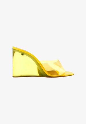 Sandale compensée jaune translucide avec bout ouvert et large bride transparente sur le pied.