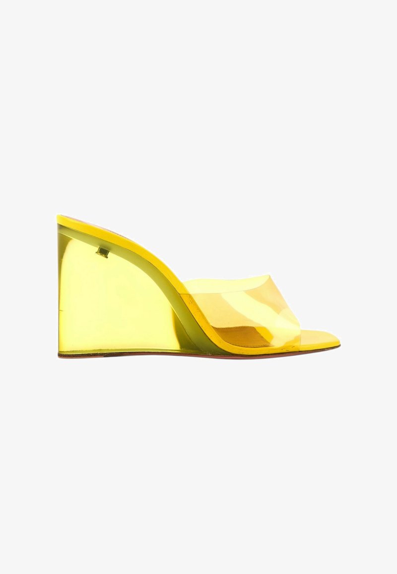 Sandale compensée jaune translucide avec bout ouvert et large bride transparente sur le pied.