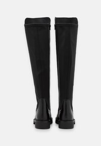 Botas negras hasta la rodilla con un exterior elegante y suave, textura de cuero contrastante en el tacón y un cierre de cremallera estilizado en la parte posterior.