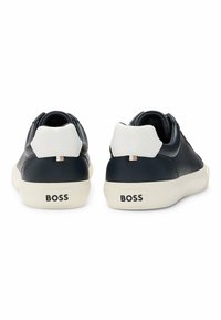 Men's sneakers in navy leather with white heel accents, round toe, and a textured finish. Logo printed on heel. White rubber sole.
