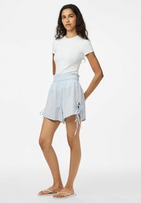 Svetlainiai mėlynai langeliais šortai su elastingu juosmeniu, šoninėmis raištelėmis ir laisvu siluetu, derinami su prigludusia balta trumpa rankove.