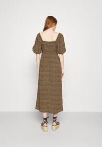 Brun blommig maxi-klänning med puffärmar och fyrkantig halsringning. Har en smockad midja och svarta remsandaler med kilklack.