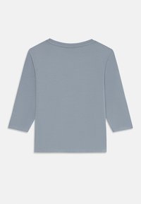 En ensfarget lys blå langermet barne T-skjorte ligger flatt, viser baksiden med rund hals og enkle sømdetaljer.