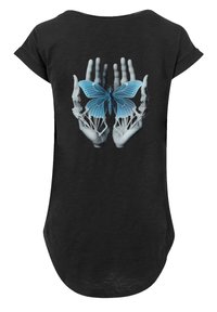 Schwarzes T-Shirt mit einem Grafikmotiv von knöchernen Händen, die einen blauen Schmetterling halten, wobei die filigranen Details im Design hervorgehoben werden.