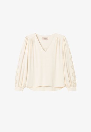 Blusa crema con scollo a V, davanti plissettato e maniche a sbuffo con ricami floreali lungo i polsini e una vestibilità morbida all'orlo.
