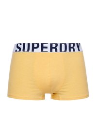 Geel katoenen boxer shorts met een witte elastische tailleband waarop de tekst "SUPERDRY" in marineblauw staat. Eenvoudig, aangesloten ontwerp zonder patronen.