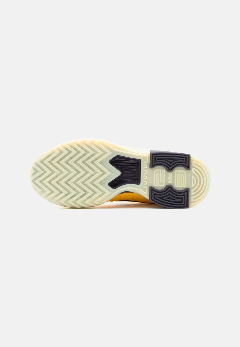 Rubber sneaker sole with a zigzag tread pattern. Yellow and white upper, featuring a black accent near the heel. Textured for traction.