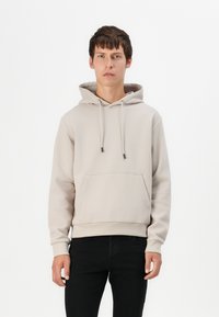 Helle beige Kapuzenjacke aus Baumwollmischung, mit einer Kordelzugkapuze, einer Fronttasche, gerippten Bündchen und einer lockeren Passform.