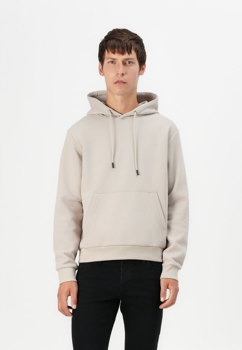 Helle beige Kapuzenjacke aus Baumwollmischung, mit einer Kordelzugkapuze, einer Fronttasche, gerippten Bündchen und einer lockeren Passform.