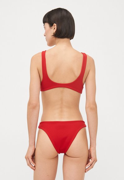 Bikini rouge avec une texture lisse, comportant un haut à dos plongeant et un bas échancré. Les deux pièces ont de larges bretelles et des coutures minimales.