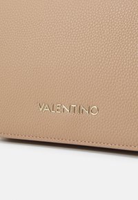 Portafoglio in pelle beige con finitura texture e logo "VALENTINO" in oro embossato sul fronte, caratterizzato da un design elegante e minimale.