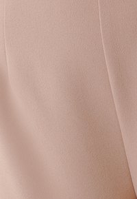 Ljust rosa textil med en slät yta. Närbild som visar fin detaljering och subtila ytskillnader.