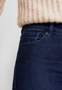 Mörkblå jeans med slim fit, med en standardknapp och dragkedjestängning, en framficka och en texturerad tyg.