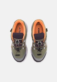 Green and gray athletic shoes with a textured upper, orange mesh lining, reflective accents, and a bungee lace system.