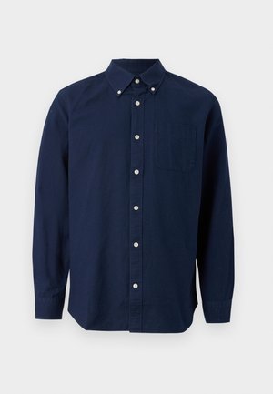 Camisa de botones de manga larga en azul marino con un bolsillo en el pecho y cuello abotonado, mostrada sobre un fondo blanco.