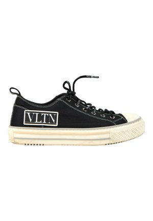 Baskets basses noires avec semelle et bout en caoutchouc blanc, lacets noirs et un patch logo rectangulaire blanc sur le côté avec l'inscription VLTN.