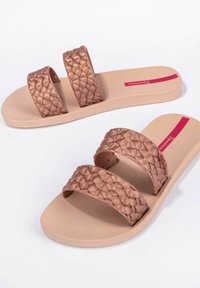 Sandalias de tiras tejiadas marrón con una plantilla texturizada de color beige claro. Cuentan con dos tiras amplias y una suela suave, adecuadas para un uso casual.