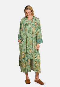 Long green floral robe featuring an oversized design, side pockets, and contrasting striped sleeves. Soft fabric with intricate patterns.