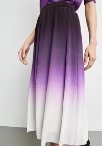 Falda midi plisada con una transición de color degradado de púrpura profundo a blanco, con un acabado texturizado y una cinturilla negra sólida.