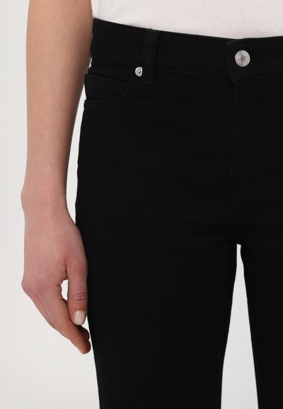Jeans in denim nero con una texture liscia, dotati di tasca frontale, chiusura a bottone e accessori in argento a contrasto. Silhouette aderente.