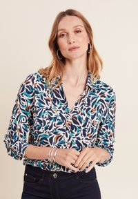 Camicia button-up con un motivo astratto blu, turchese, arancione e bianco; maniche lunghe con polsini; due tasche frontali; tessuto leggero.