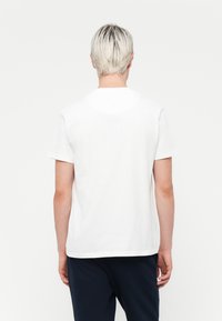White cotton t-shirt with short sleeves, ribbed crew neckline, and a straight hem. Smooth texture and relaxed fit.