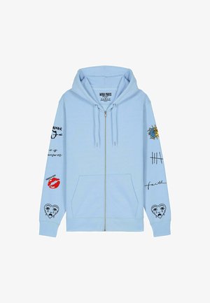 Helevale sinine tõmblukuga kapuutsiga jakk, mis on valmistatud puuvilla segust. Omab trükitud graafikat varrukatel, sealhulgas huuli, silmi ja fraase. Reguleeritav nööriga kapuuts.