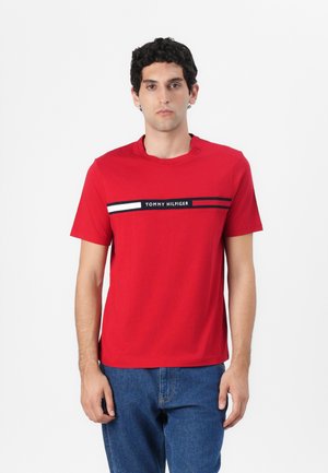 Red cotton t-shirt featuring a crew neck, short sleeves, and a horizontal stripe design with blue and white accents and "TOMMY HILFIGER" logo.