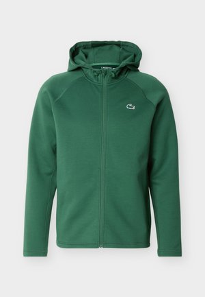 Felpa verde con cappuccio e cerniera integrale, maniche lunghe e piccolo logo coccodrillo ricamato sul petto a sinistra.