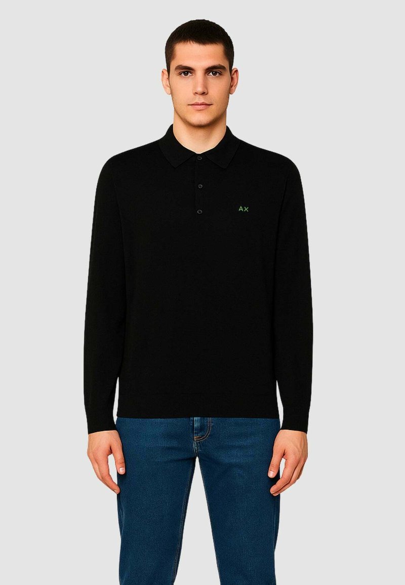 Polo a maniche lunghe nera realizzata in morbido tessuto, con una chiusura a tre bottoni e un piccolo logo verde sul petto.