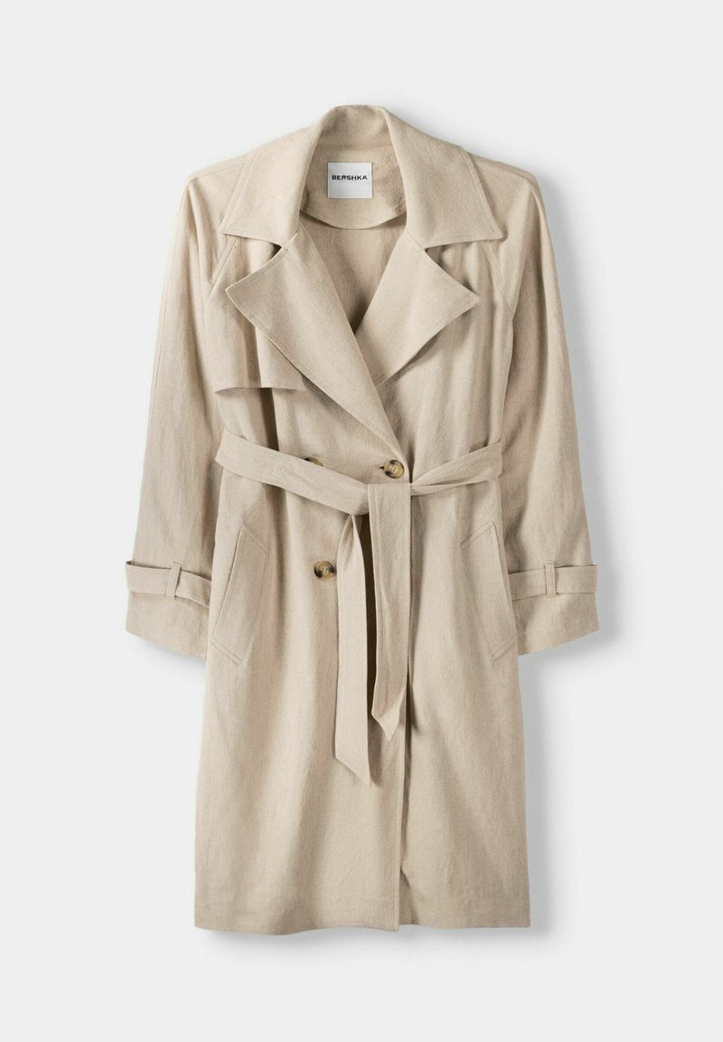 Trench coat beige realizzato in tessuto texturizzato, caratterizzato da un ampio colletto, due tasche frontali, una cintura e due chiusure a bottone.