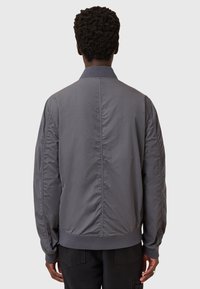 Giacca bomber grigia realizzata in materiale leggero, con colletto a coste, polsini elasticizzati e una texture liscia con dettagli di cucitura sottili.