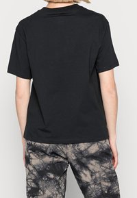 Sort bomulds T-shirt med rund hals og korte ærmer, der har en glat tekstur og en standard pasform, vist fra ryggen.