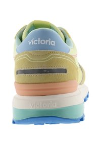 Achteraanzicht van een meerkleurige Victoria sneaker met suède hiel, lichtblauwe en gele bovenzijde, en een gelaagde zool in blauw, groenblauw, roze en wit.