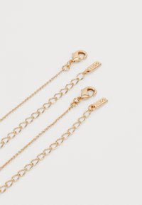 Catene di gioielli in tono oro con stili di anelli variabili; dotate di chiusure a gancio e etichette di marca. Superficie liscia con una finitura lucida.