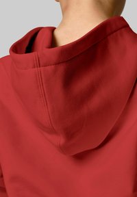 Red hooded sweatshirt displaying a smooth texture and prominent stitching along the neckline and hood. The fabric appears soft and thick.