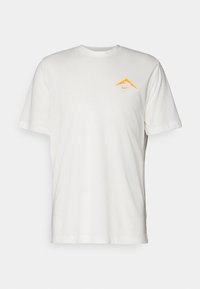 Camiseta de algodón blanca con mangas cortas, que presenta un logo de Nike triangular naranja en el lado izquierdo del pecho.