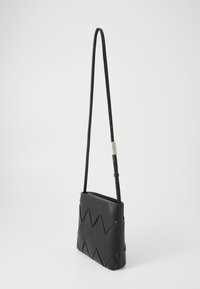 Borsa a tracolla nera in pelle con design intrecciato, forma rettangolare, tracolla regolabile e texture liscia. Dettaglio hardware metallico sottile.