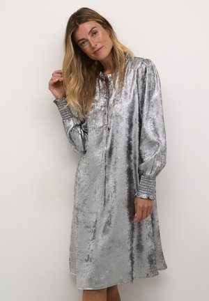 Kimallellinen hopeinen mekko, jossa on rento istuvuus, pitkät hihat, napitettu eturivi ja teksturoidut hihansuut. Pehmeä metallinen kangas, jossa on hieno kiilto.
