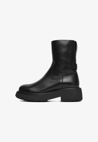 Botas de tobillo de cuero negro con suela de plataforma gruesa, diseño elegante, tirador y paneles laterales elásticos para facilitar el calzado.