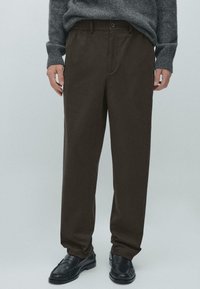 Pantaloni marroni a vestibilità comoda con fascia elastica in vita e bottone frontale. Realizzati in tessuto liscio, adatti per un look casual.
