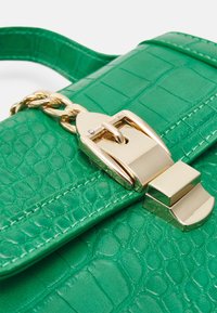 Borsa a tracolla in ecopelle verde con un motivo testurizzato a coccodrillo, hardware dorato e una chiusura a scatto prominente con un accento a catena.