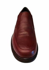 Zapato de piel burdeos tipo slip-on con textura suave, punta redondeada y suela negra en contraste. Detalle de costura mínima en el borde.