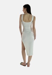 Vestido midi blanco ajustado con escote en la espalda, abertura lateral y tejido suave y elástico. Presenta tirantes anchos y un diseño sin costuras.